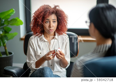Woman holding sleeping pills and speaking with psychologist 59342718