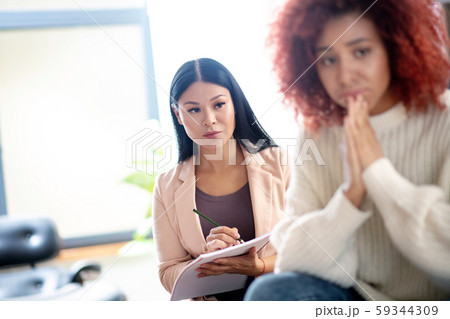 Asian psychoanalyst making notes while listening to patient 59344309