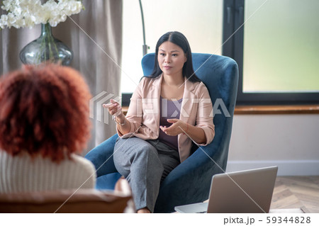 Asian professional female psychologist speaking with client 59344828