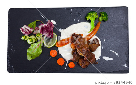 Tasty chicken heart with cream sauce served with vegetables at plate 59344940