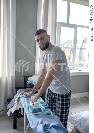 Dark-haired young businessman ironing in the morning Dark-haired young businessman ironing in the morning 59345178