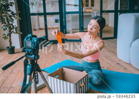Fitness blogger showing resistance band while filming video 59346235