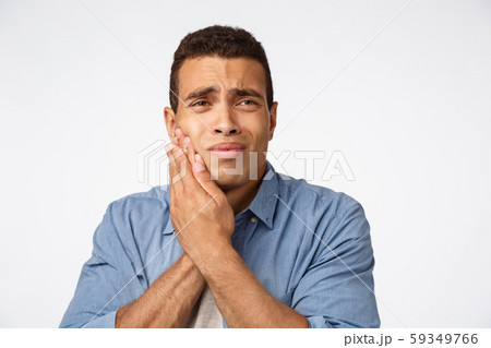 Medicine, people and emotions concept. Upset gloomy young man have discomfort, touch cheek and 59349766