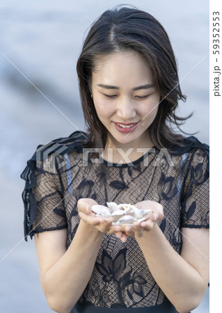 海岸の波打ち際で貝殻を拾い集める若い女性のライフスタイル 59352553