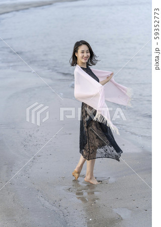 海岸の波打ち際を裸足で優雅に散歩する若い女性のライフスタイル一人旅 59352773