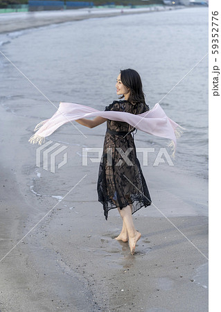 海岸の波打ち際を裸足で優雅に散歩する若い女性のライフスタイル一人旅 59352776