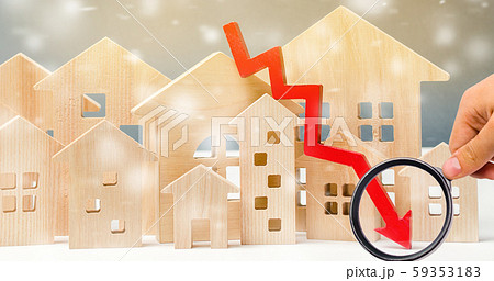 Miniature wooden houses and down arrow. The concept of low housing demand. Discounts for real estate in the winter. Mortgage, loan. Cheap cost. Christmas Snowflakes 59353183