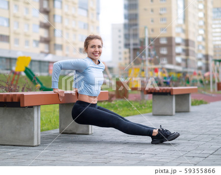 Caucasian fit redhead girl doing reverse push ups on a bench in sports yard, selective focus Caucasian fit redhead girl doing reverse push ups on a bench in sports yard, selective focus 59355866