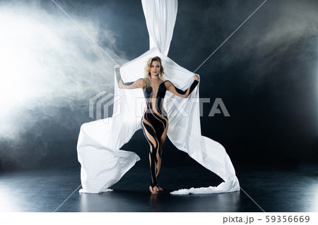 A young girl performs the acrobatic elements in the air trapeze. Studio shooting performances on a 59356669