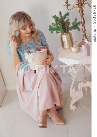 Young beautiful blonde woman holding a box of new year toys Young beautiful blonde woman holding a box of new year toys 59356710