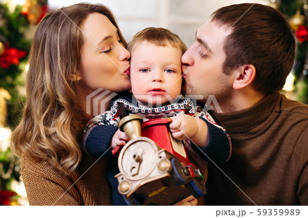 Loving parents kissing son holding toy train. Loving parents kissing son holding toy train. 59359989