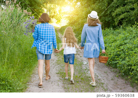 Family in the summer on forest rural road. Mother and daughter hold hands, view from the back. Family in the summer on forest rural road. Mother and daughter hold hands, view from the back. 59360638