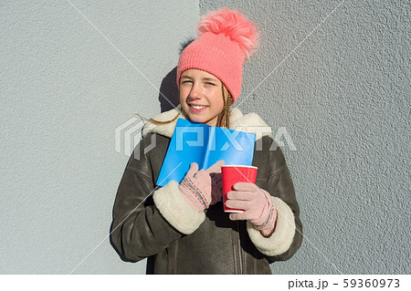 Winter outdoor portrait of young female student with book and cup Winter outdoor portrait of young female student with book and cup 59360973