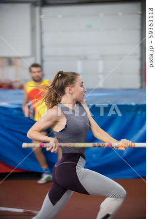 Pole vaulting indoors - young sportive woman with ponytail running with a pole in the hands Pole vaulting indoors - young sportive woman with ponytail running with a pole in the hands 59363118