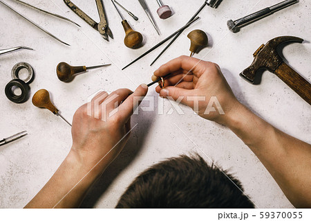 The jeweler polishes the gold ring at his workplace 59370055