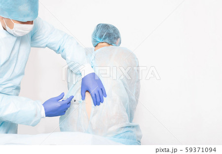 A male anesthesiologist performs a surgical procedure that introduces epidural anesthesia into the A male anesthesiologist performs a surgical procedure that introduces epidural anesthesia into the 59371094