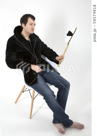 young man in a fur coat sitting in a white chair 59374818