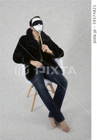 young man in a fur coat sitting in a white chair young man in a fur coat sitting in a white chair 59374821