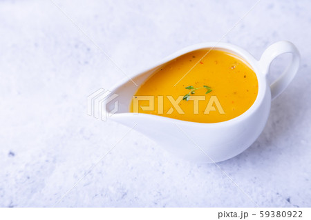Orange sauce for duck (poultry) in a white gravy boat. Close-up, selective focus. Orange sauce for duck (poultry) in a white gravy boat. Close-up, selective focus. 59380922