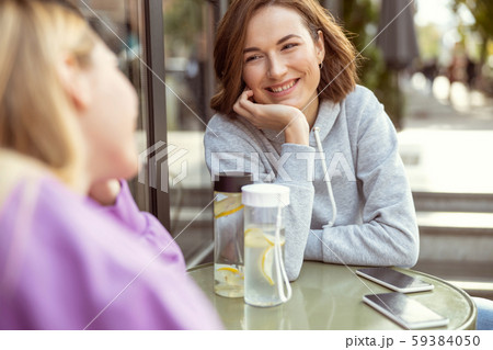Pleased young woman talking with her friend Pleased young woman talking with her friend 59384050