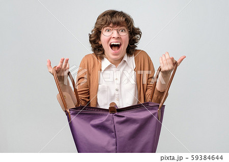 Young funny woman with big shopping bag being happy to find something inside Young funny woman with big shopping bag being happy to find something inside 59384644