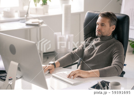 Serious manager concentrating on work while sitting in front of computer screen Serious manager concentrating on work while sitting in front of computer screen 59391695