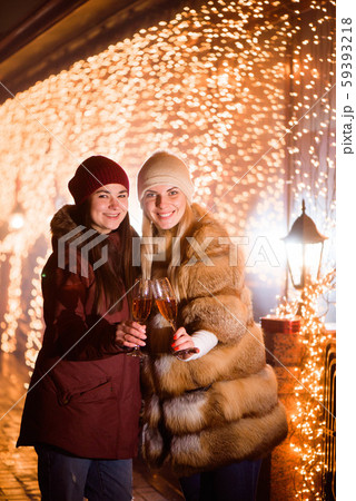 Girls enjoying champagne. Outdoor portrait of ladies on light background. Girls enjoying champagne. Outdoor portrait of ladies on light background. 59393218