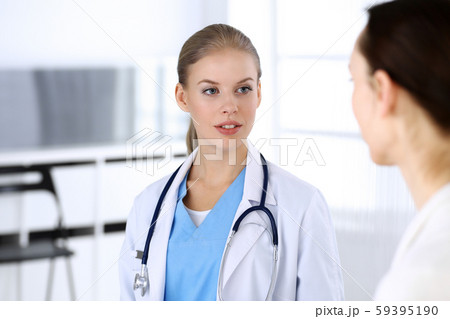 Doctor and patient during consultation. Physician at work filling up medication history record while Doctor and patient during consultation. Physician at work filling up medication history record while 59395190