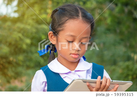 Happy little girl holding tablet PC outdoors in 59395315