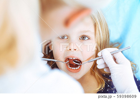 Little baby girl sitting at dental chair with open mouth during oral check up while doctor. Visiting 59398609