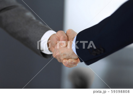 Business people shaking hands while standing with colleagues after meeting or negotiation, close-up Business people shaking hands while standing with colleagues after meeting or negotiation, close-up 59398808