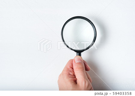 Magnifier in a man's hand on a white background. 59403358
