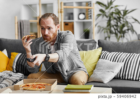 Single Man Eating Pizza while Watching TV 59406942