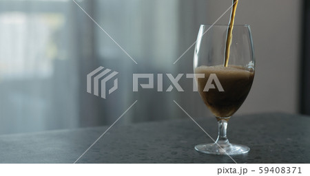 pour stout beer into tulip glass on terrazzo countertop with copy space 59408371