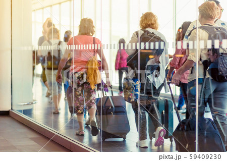 Back view of passengers and traveling luggage walking the airplane boarding corridor from the terminal to the plane. 59409230