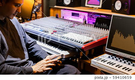 sound engineer listening music, surfing internet and playing social media on smartphone in studio 59410659