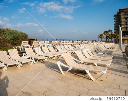 海岸沿いのヤシの木が並ぶレジャーホテルのプール脇に並ぶビーチベッド　テルアビブにて 59410740