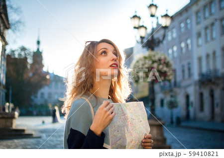 Happy excited adult girl is looking at the paper map and searching for direction early in the 59410821