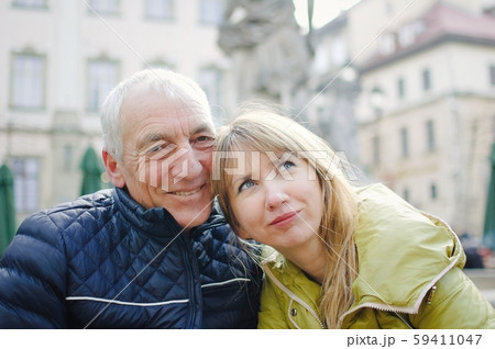Handsome elderly man is embracing his young blonde wife spending time together outdoors in the 59411047