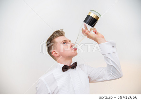 Young man drinking from glass bottle against a white background. Cheerful face. 59412666