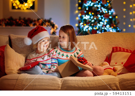 Child at Christmas tree. Kids at fireplace on Xmas Child at Christmas tree. Kids at fireplace on Xmas 59413151