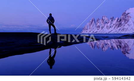 Man standing at Tungeneset, his mirror reflection in the water, mountains in the background, Senja Man standing at Tungeneset, his mirror reflection in the water, mountains in the background, Senja 59414342