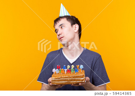 Crazy cheerful young man in glasses and paper congratulatory hats holding cakes happy birthday 59414365