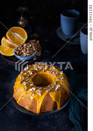 Bundt cake, orange cake with walnuts and yellow sugar icing with turmeric spice. Dark background Bundt cake, orange cake with walnuts and yellow sugar icing with turmeric spice. Dark background 59415192