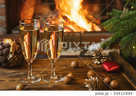 Christmas composition - Two glasses with champagne on a wooden table near a Christmas tree in a room Christmas composition - Two glasses with champagne on a wooden table near a Christmas tree in a room 59415994