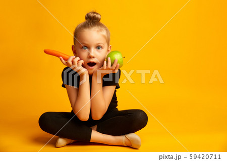Puzzled little dancer choosing between a green apple and a carrot Puzzled little dancer choosing between a green apple and a carrot 59420711