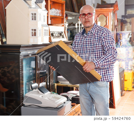 Mature man carefully examining antiques Mature man carefully examining antiques 59424760