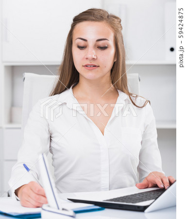Woman employee is working with documents and laptop 59424875