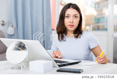Young woman student working with laptop and pen at table Young woman student working with laptop and pen at table 59425018