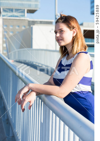 Girl in blue dress standing on city bridge 59425889
